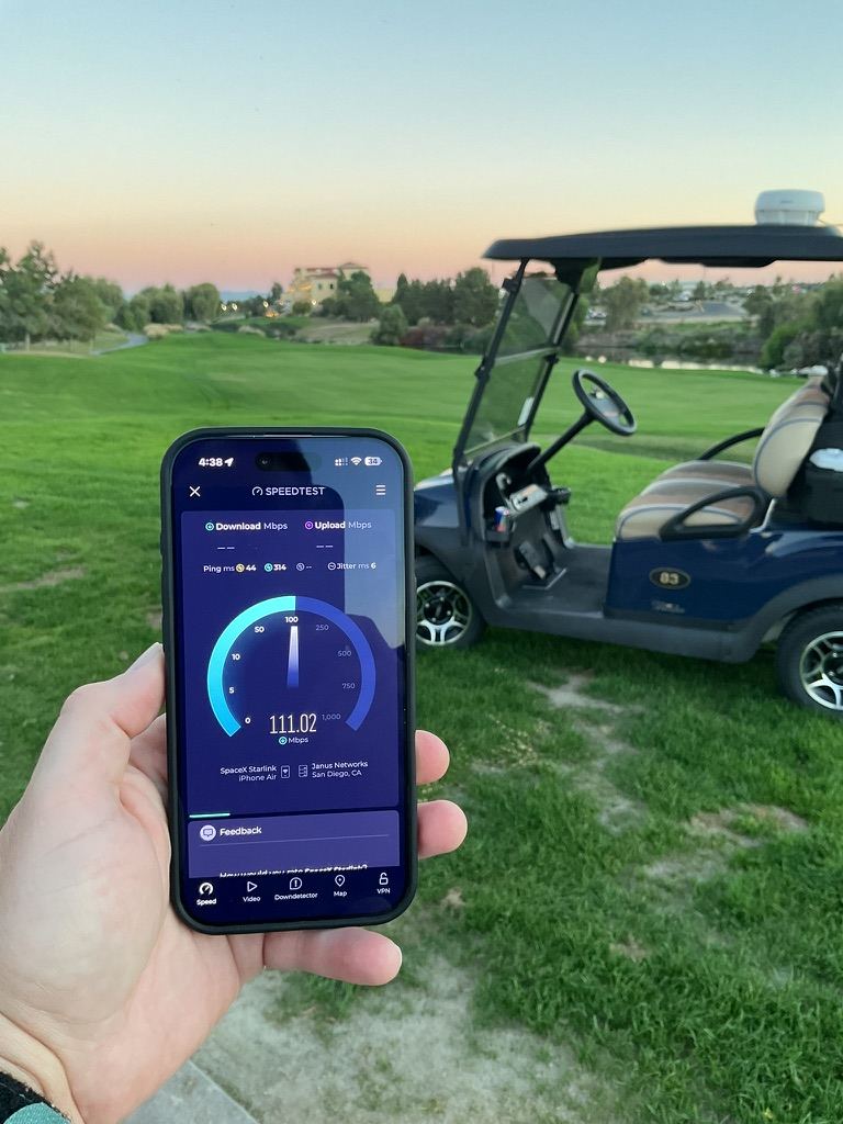 A phone showing a 111 Mbps speed test result on the fairway at sunset, with a golf cart alongside
