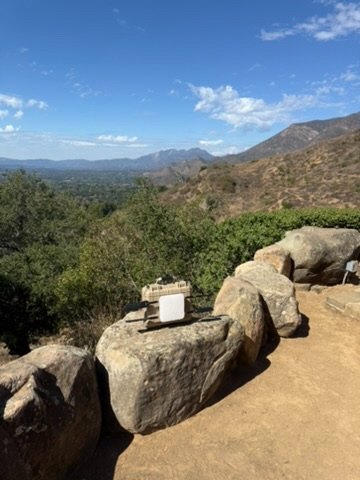 A small white Bright5G enclosure sitting on a boulder at the edge of campus, overlooking the Ojai valley
